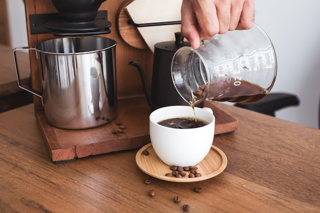 A hand pouring drip coffee into a mug