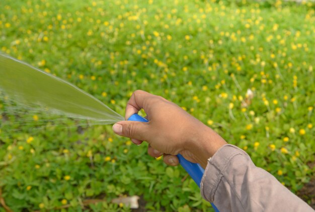 Hand on Pouring fresh water in the glass with the green nature background.