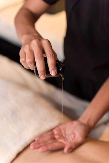 Hand pouring oil for massage in spa