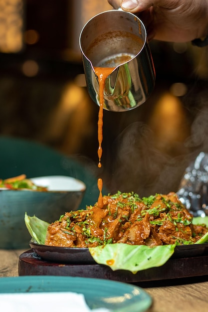 A hand pouring a sauce over a plate of food