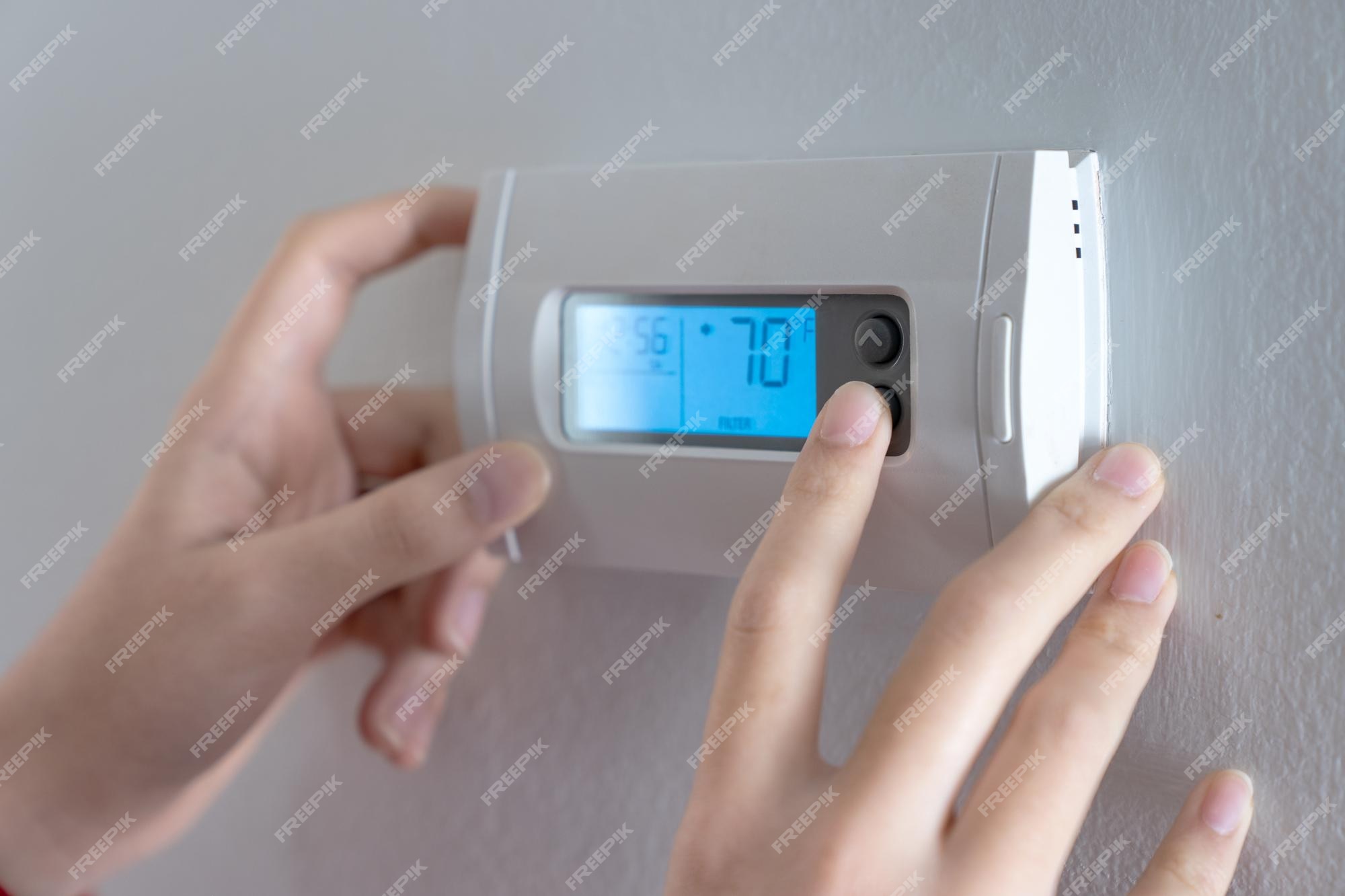 Premium Photo  Hand press indoor room thermostat to lower the temp