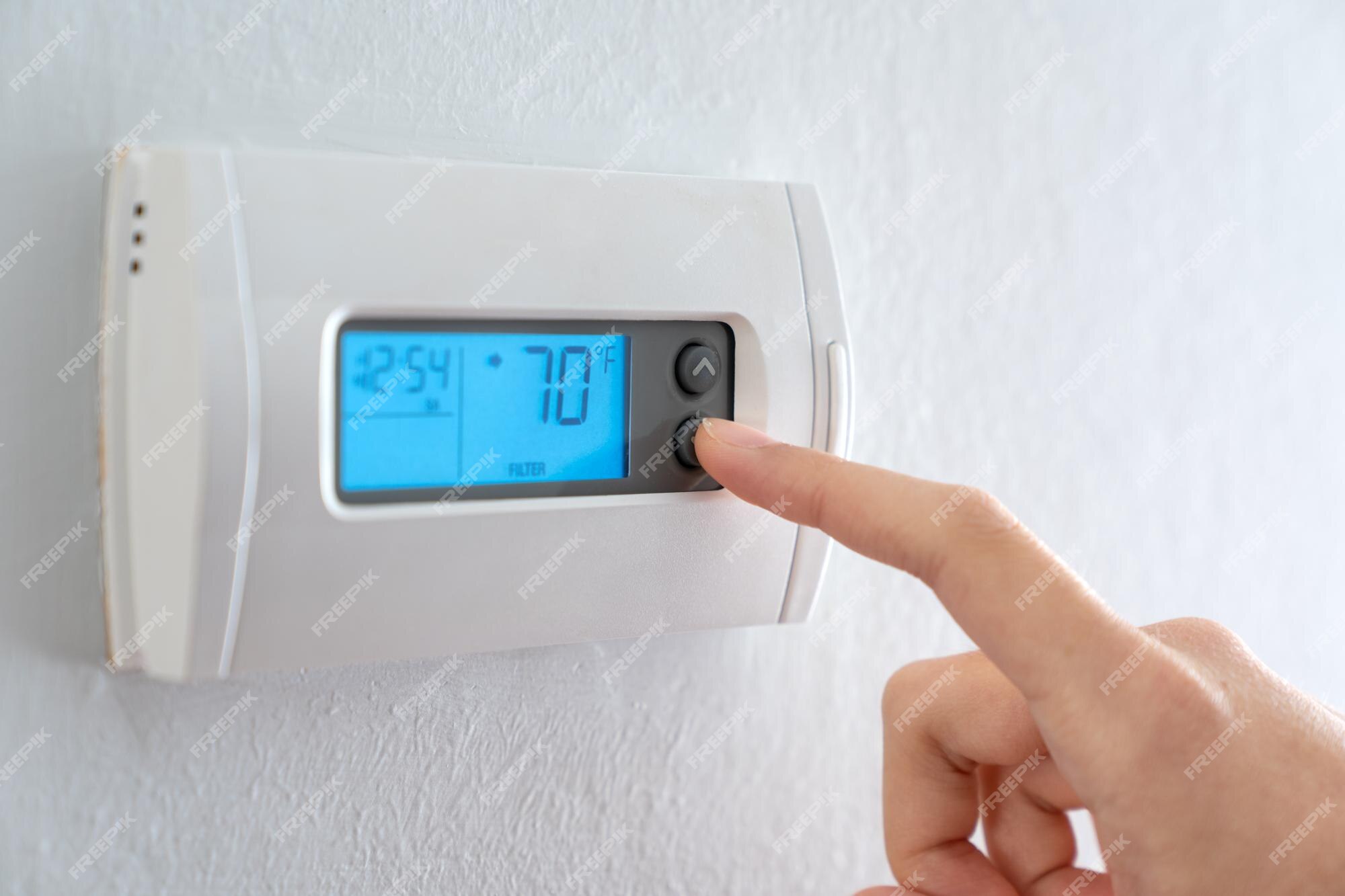 Premium Photo  Hand press indoor room thermostat to lower the temp