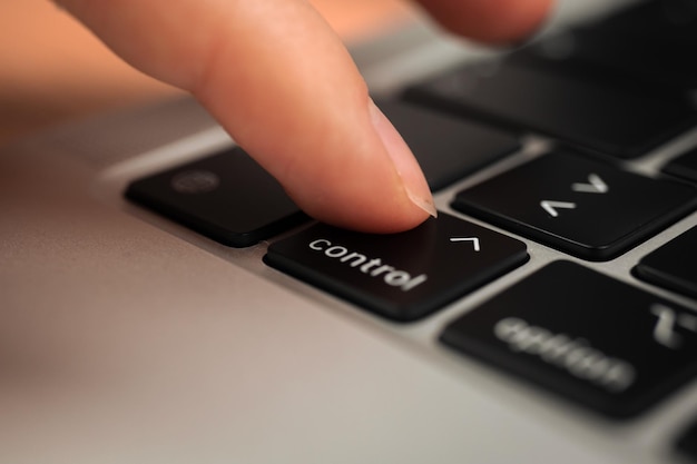 Hand pressing control key on modern laptop keyboard control
sign and symbol closeup