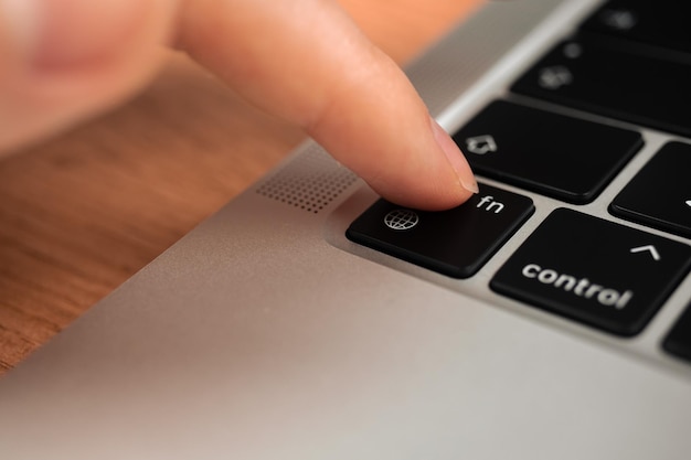 Hand pressing the globe key on modern laptop keyboard The globe sign and symbol closeup