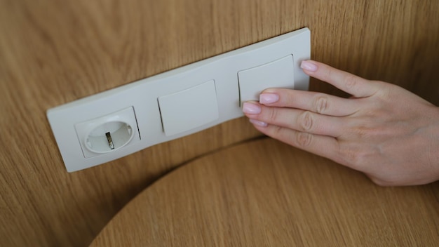 家のクローズ アップの壁にライト スイッチを押す手