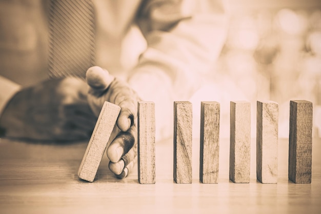 Photo hand prevent wooden block not falling domino