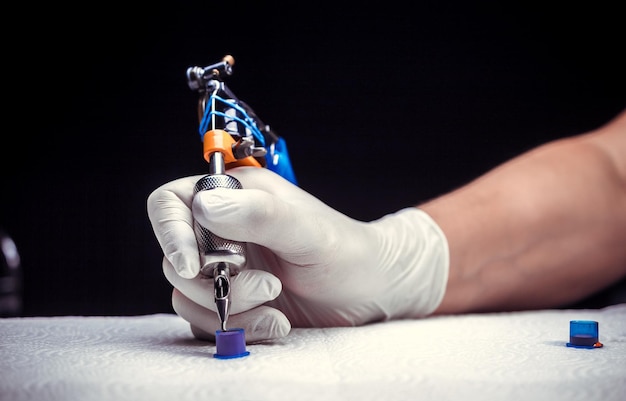 Foto mano di un tatuatore professionista con una pistola per tatuaggi