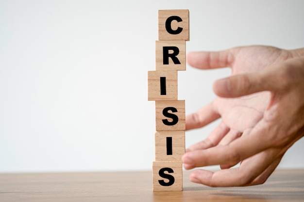 Foto la mano protegge il blocco di cubi di legno che stampa il testo sullo schermo. concetto di crisi economica e finanziaria.