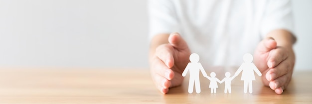 Hand protecting family on wood table Healthcare and life insurance concept