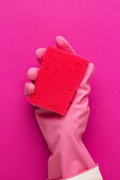 Hand in protective glove holding red sponge