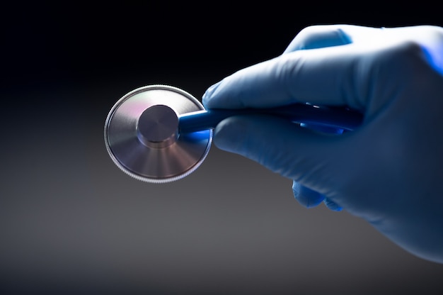 Hand in a protective glove holding a stethoscope close up view.