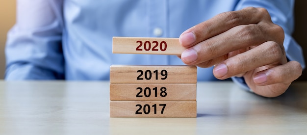 hand pulling 2020 wooden building blocks on table background