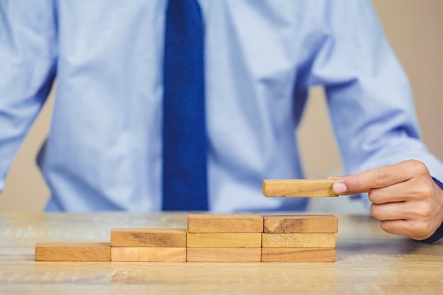 Foto tirare fuori o posizionare un blocco di legno sulla torre, piano e strategia nel mondo degli affari