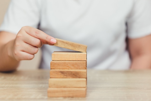 Hand pulling out or placing wood block on the tower, plan and strategy in business