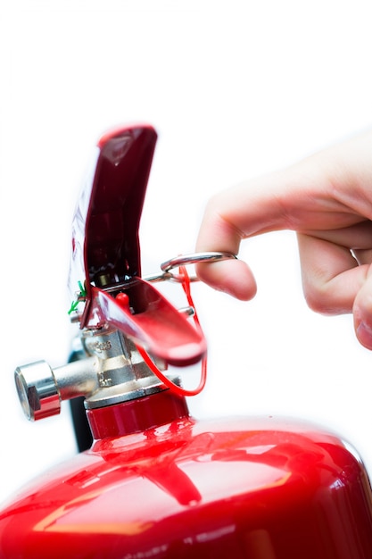 Hand pulling safety pin from fire extinguisher