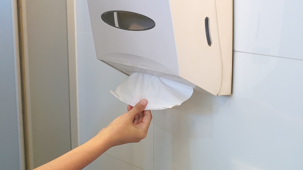 Hand pulling toilet paper in the bathroom