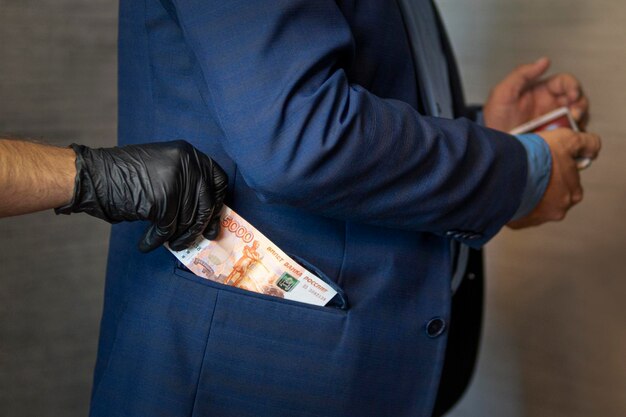 Hand pulls paper money out of his jacket pocket A thief robbed a businessman Cash theft criminal concept