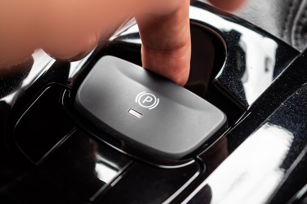 Hand push on electronic handbrake button in luxury modern car