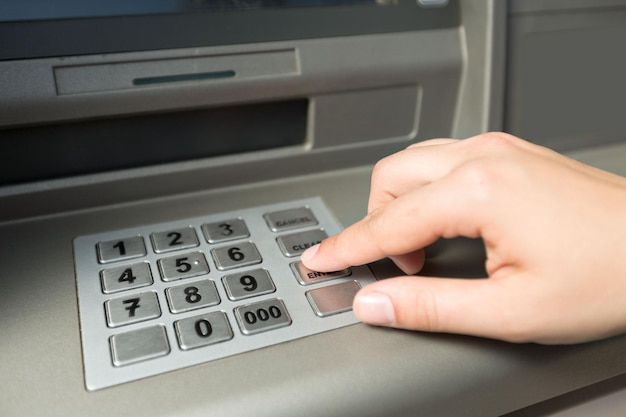 Hand pushing button on ATM, close up