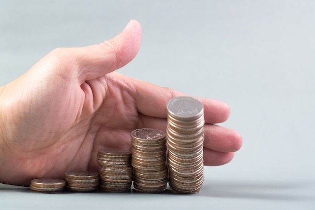 Hand pushing a pile of coins, column of coins falls