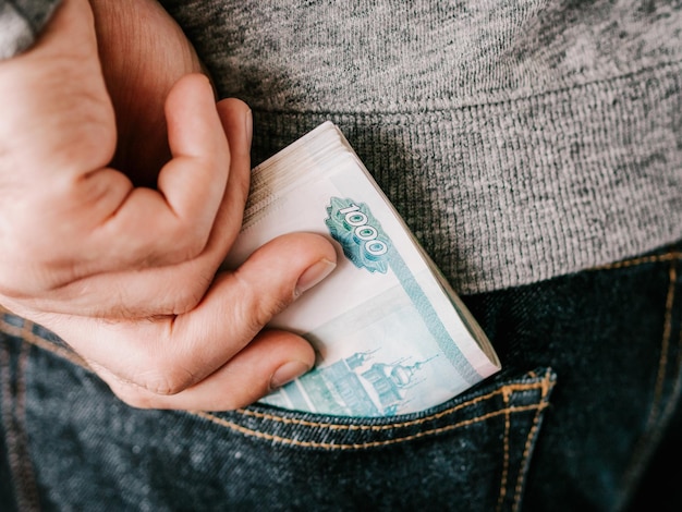 Photo hand put rubles in jeans pocket