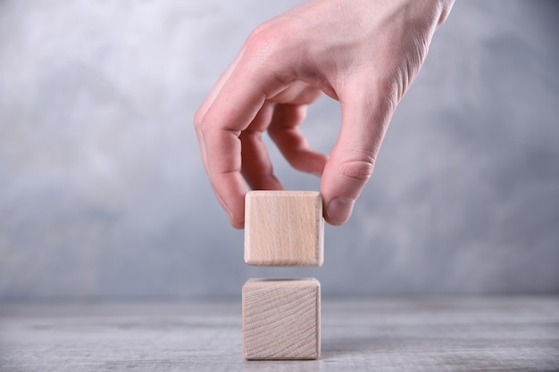 Photo hand puts blank wooden cube