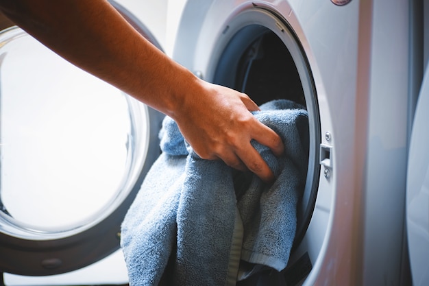 Hand and puts the laundry into the washing machine