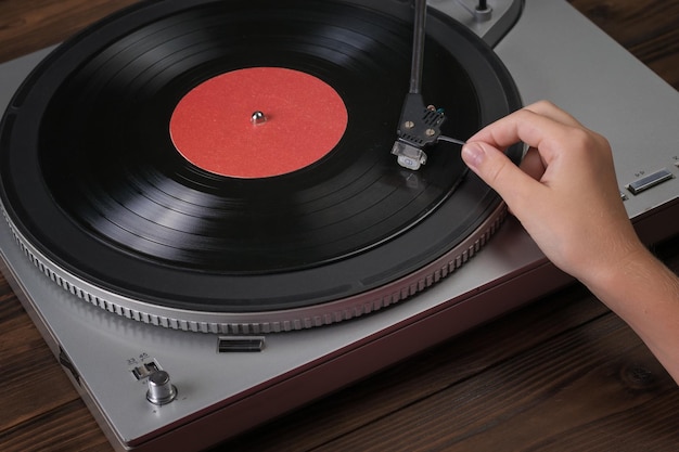 The hand puts the needle down on the vinyl record