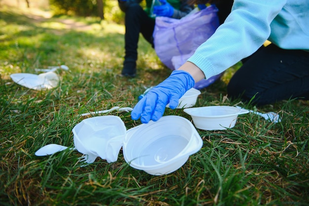 La mano mette i detriti di plastica nel sacco della spazzatura nel parco