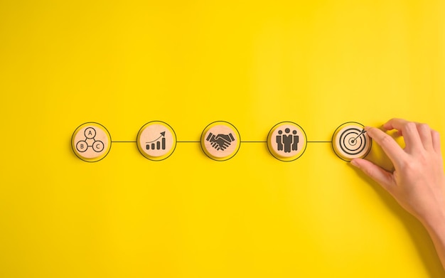 Hand putting business icons on wooden cubic blocks