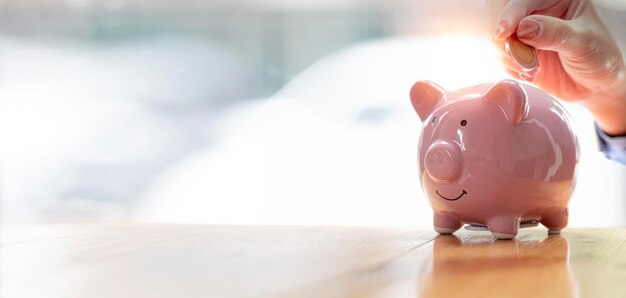 돼지 저금통에 동전을 넣는 손 미래 투자 및 은퇴 개념을 위한 돈 절약