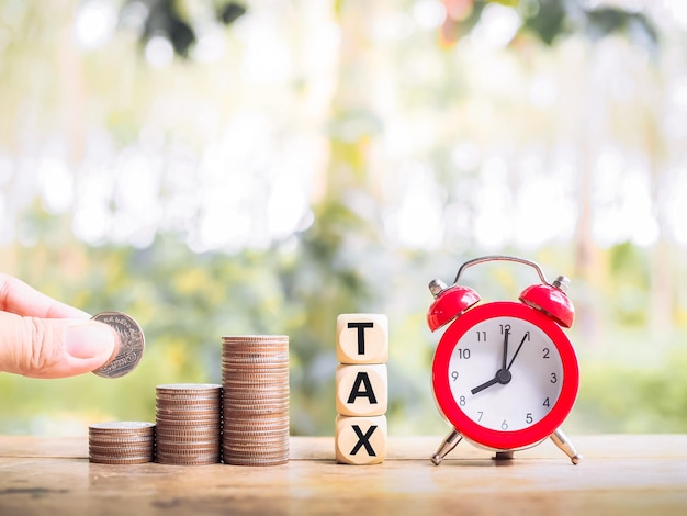 hand putting coin in stack of coins with red alarm, save money for paying tax in the future