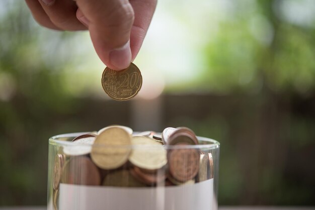 Hand putting coins in jar with money stack step growing growth saving money