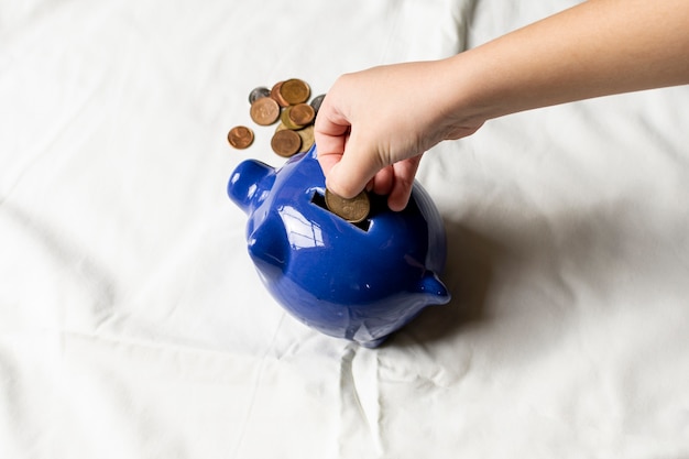 Photo hand putting coins in a piggy bank