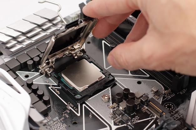 Hand putting a CPU on a motherboard of a computer.