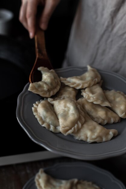 Hand putting dumplings into a plate to serve in the kitchen