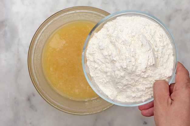 Hand putting flour into butter in glass bowl