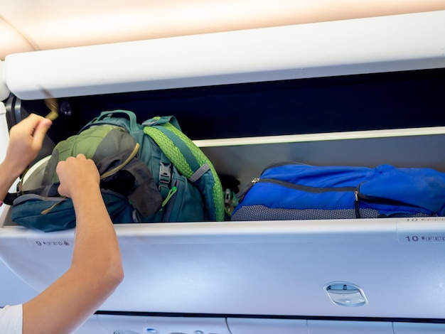 Hand putting green backpack on airplane locker