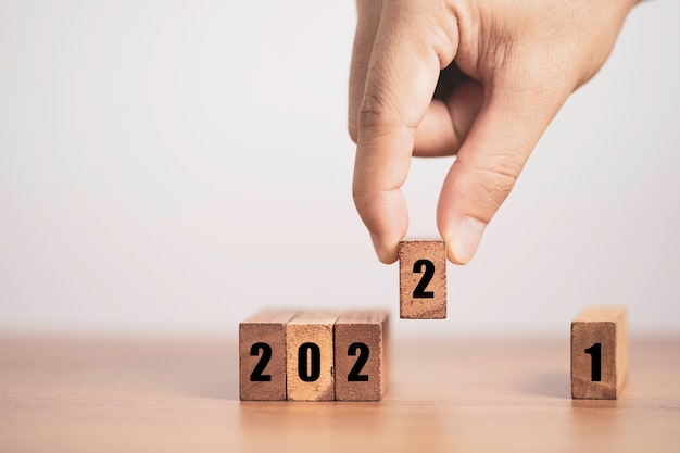 Hand putting number two for replace number one to change 2021 to 2022 year. merry christmas and happy new year concept