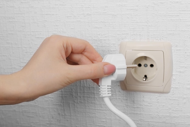 Hand putting plug in electricity socket close up