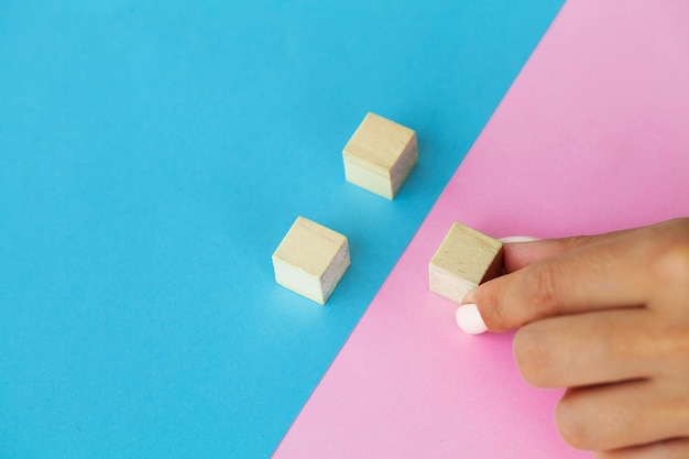 Hand putting and stacking blank wooden cubes on table