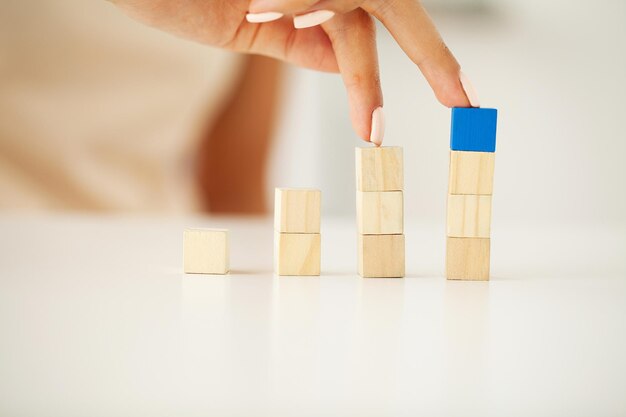 Hand putting and stacking blank wooden cubes on table