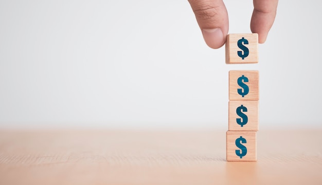 Hand putting and stacking Dollar sign or USD which print screen on wooden cubes block. Dollar is main exchange currency in the world.