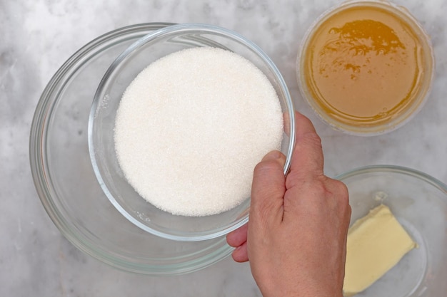 Hand putting sugar into bowl cooking recipe baking cake medovik
