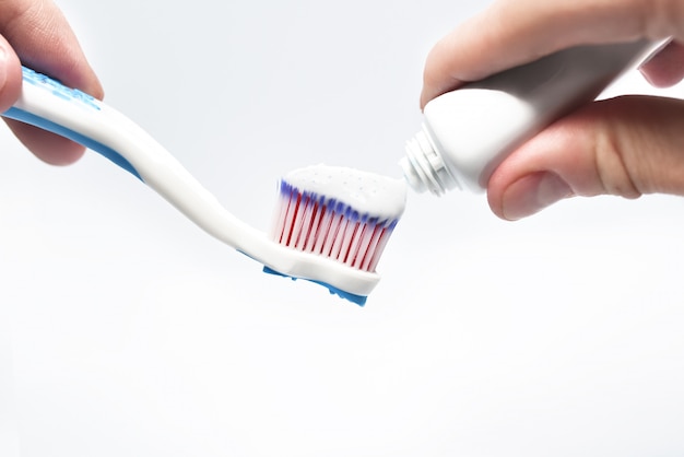 Hand putting toothpaste on toothbrush