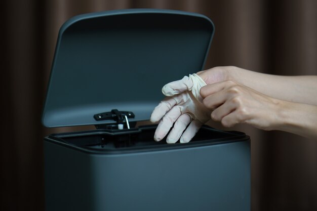 Hand putting used dirty surgical glove to  a garbage bin. mask protect dust and corona virus in trash.