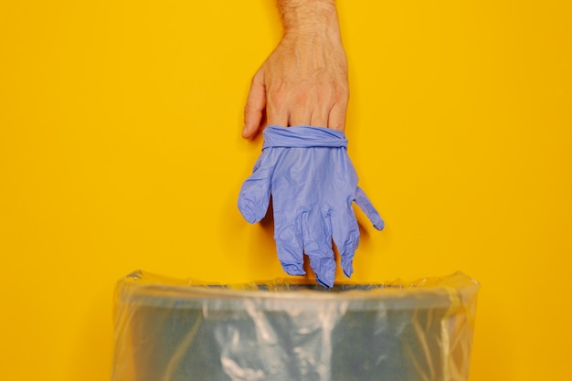 Hand putting used dirty surgical glove to a garbage bin