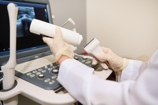 Hand of a radiologist doctor holding an ultrasound transducer and contact gel getting ready for a diagnosis Ultrasonography USG