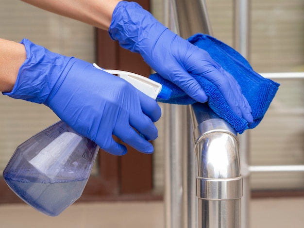 Hand rail being disinfected by hands with surgical gloves