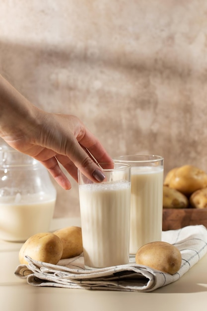 The hand reaches for a glass of potato milk Lactosefree milk